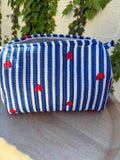 Une trousse de toilette en coton matelassé bleu et blanc à rayures, imprimée de petits cœurs rouges en blockprint artisanal