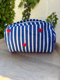 Une trousse de toilette en coton matelassé bleu et blanc à rayures, imprimée de petits cœurs rouges en blockprint artisanal