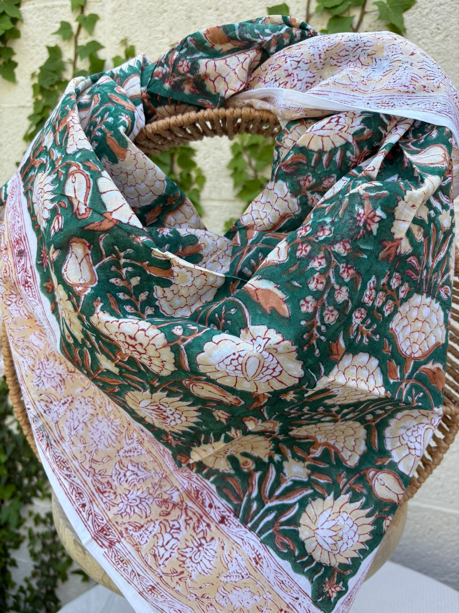 Foulard artisanal en tissu léger, fond blanc avec motifs floraux délicats imprimés à la main (style block print) dans des tons pastel d'ocre, de vert. Le tissu est fluide et légèrement texturé