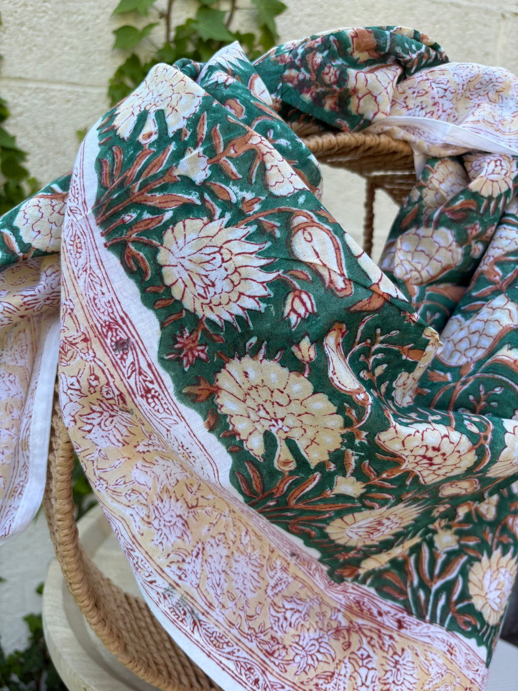 Foulard artisanal en tissu léger, fond blanc avec motifs floraux délicats imprimés à la main (style block print) dans des tons pastel d'ocre, de vert. Le tissu est fluide et légèrement texturé