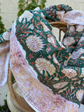 Foulard artisanal en tissu léger, fond blanc avec motifs floraux délicats imprimés à la main (style block print) dans des tons pastel d'ocre, de vert. Le tissu est fluide et légèrement texturé