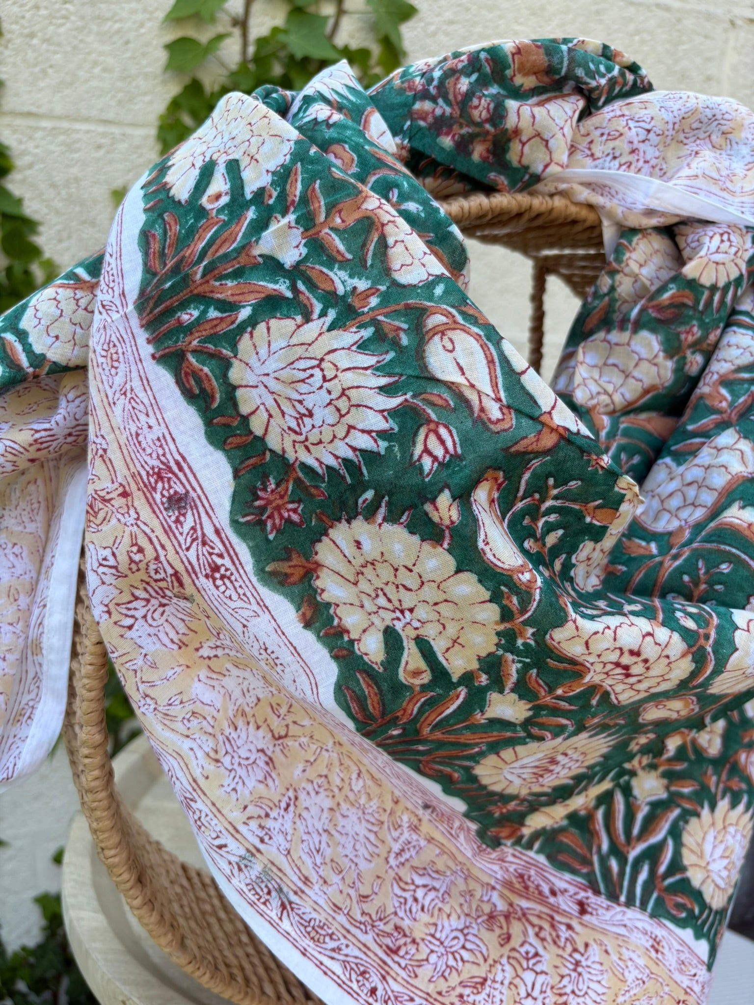 Foulard artisanal en tissu léger, fond blanc avec motifs floraux délicats imprimés à la main (style block print) dans des tons pastel d'ocre, de vert. Le tissu est fluide et légèrement texturé