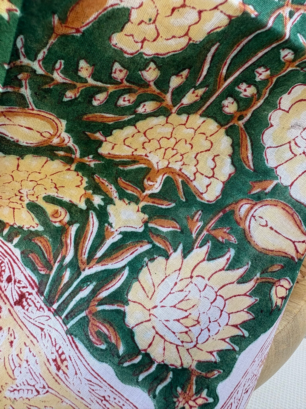 Foulard artisanal en tissu léger, fond blanc avec motifs floraux délicats imprimés à la main (style block print) dans des tons pastel d'ocre, de vert. Le tissu est fluide et légèrement texturé