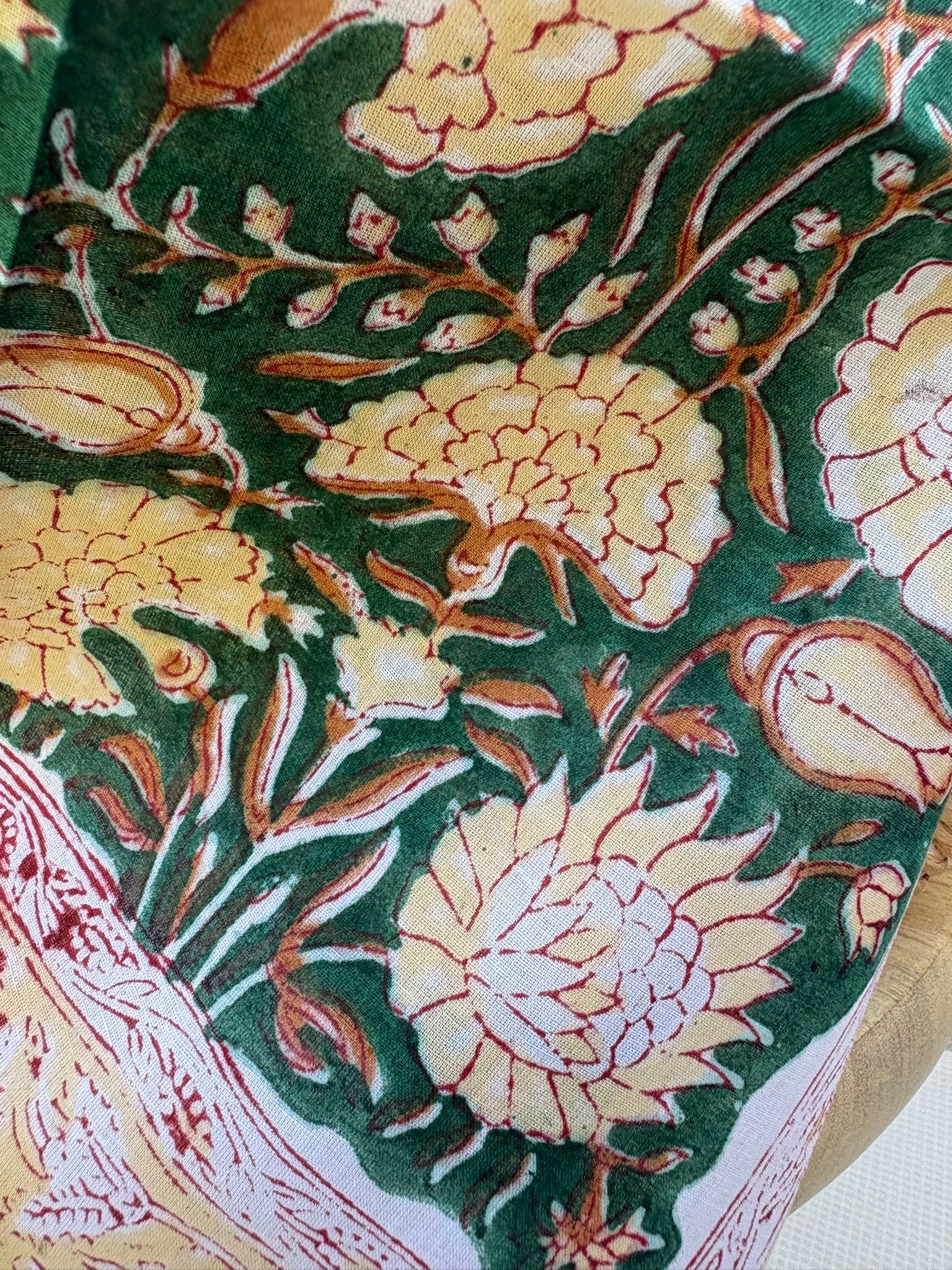 Foulard artisanal en tissu léger, fond blanc avec motifs floraux délicats imprimés à la main (style block print) dans des tons pastel d'ocre, de vert. Le tissu est fluide et légèrement texturé