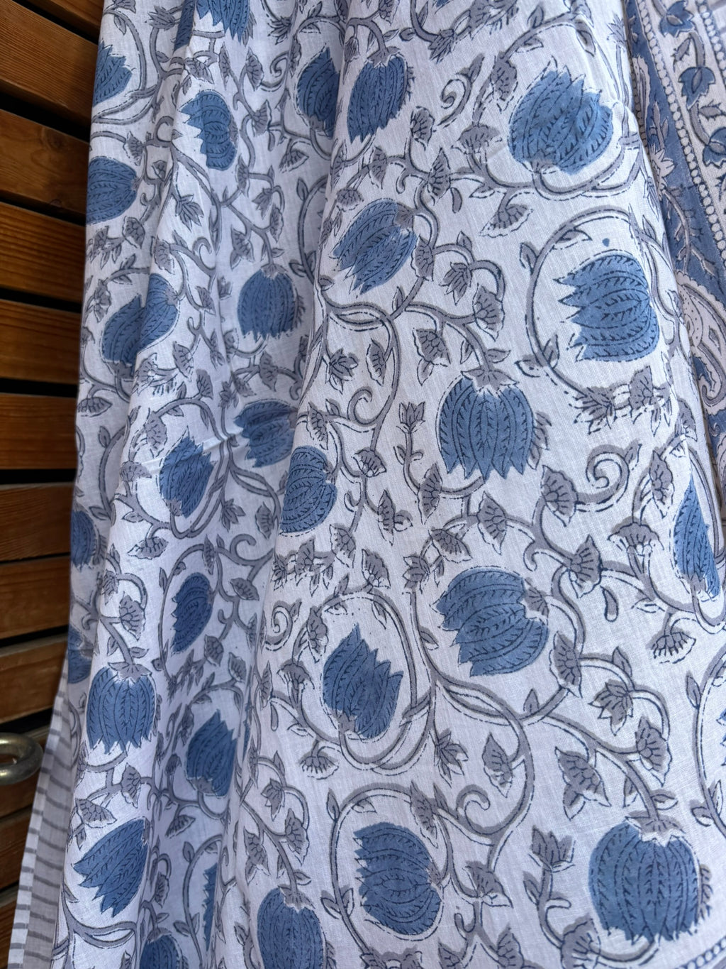 Paréo en coton léger avec impression artisanale indienne de type block print. Il présente un motif floral et végétal détaillé aux teintes bleu ardoise et gris sur un fond blanc, structuré par de larges bordures ornées et des finitions à fines rayures. 