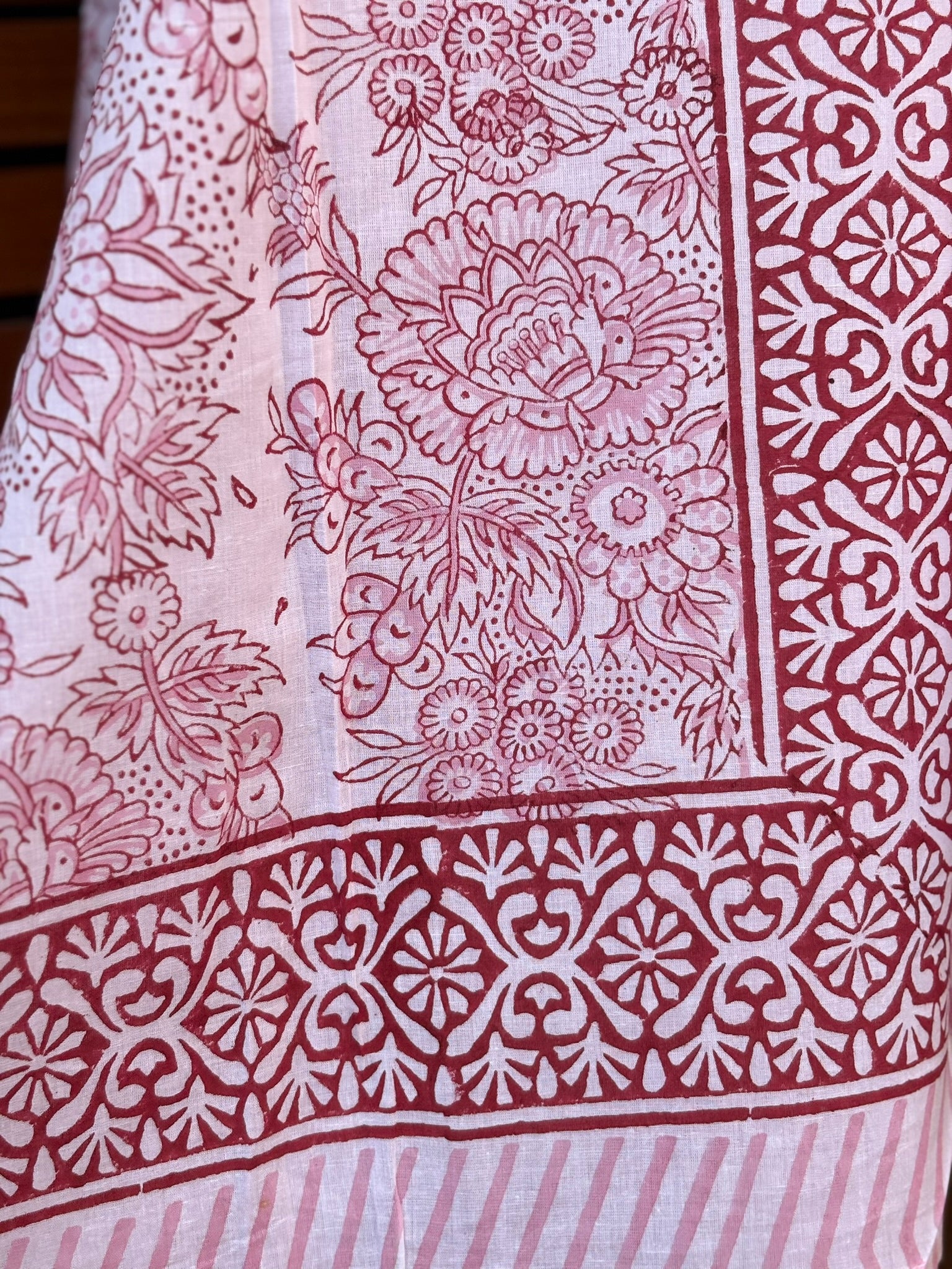 Paréo en coton léger avec impression artisanale indienne de type block print, présentant un motif floral complexe et une large bordure ornementale géométrique de couleur rouge écarlate sur fond blanc. 