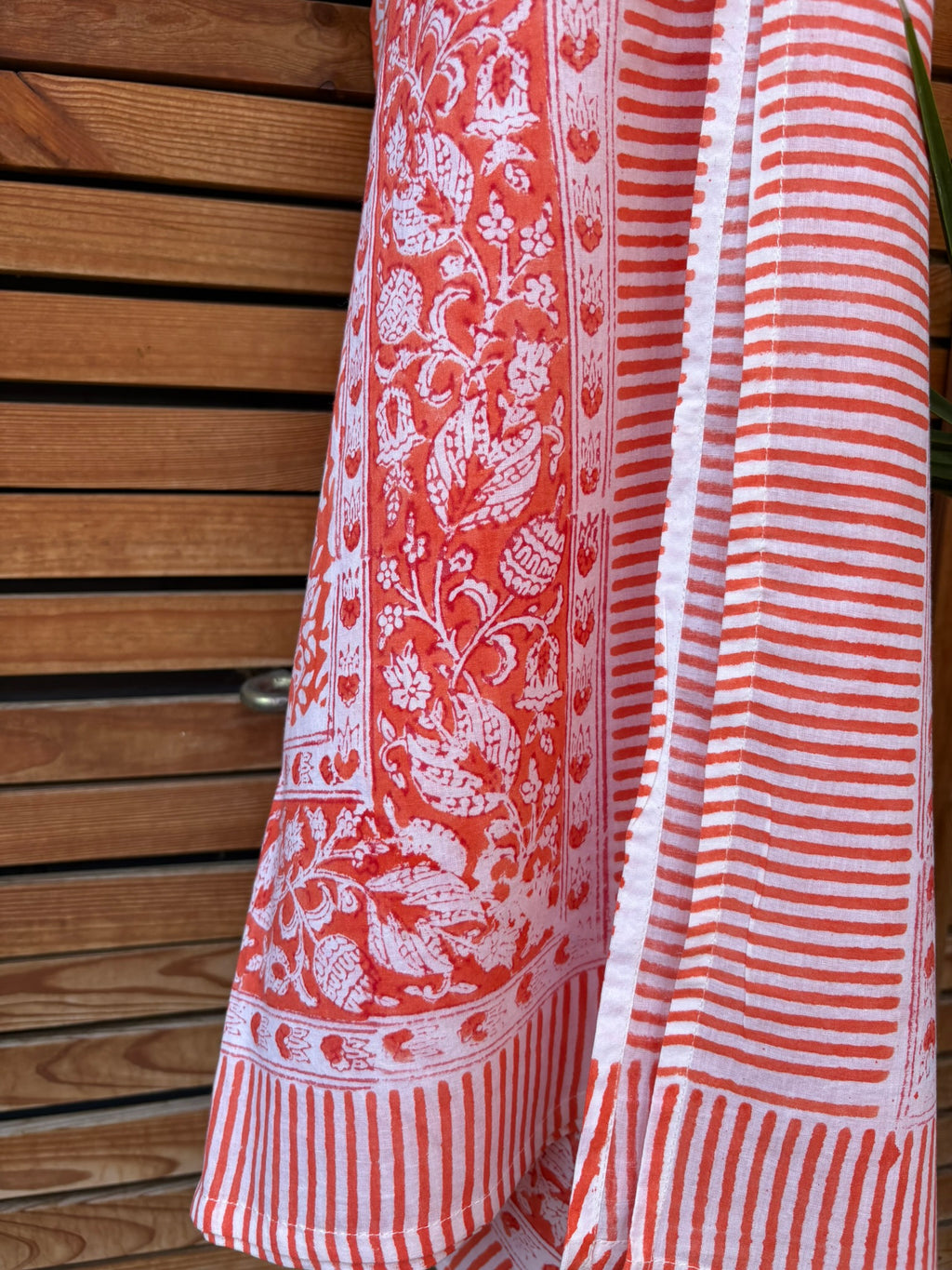 Paréo en coton léger avec impression artisanale indienne de type block print, présentant un motif floral complexe et une large bordure ornementale géométrique de couleur corail vif sur fond blanc. 