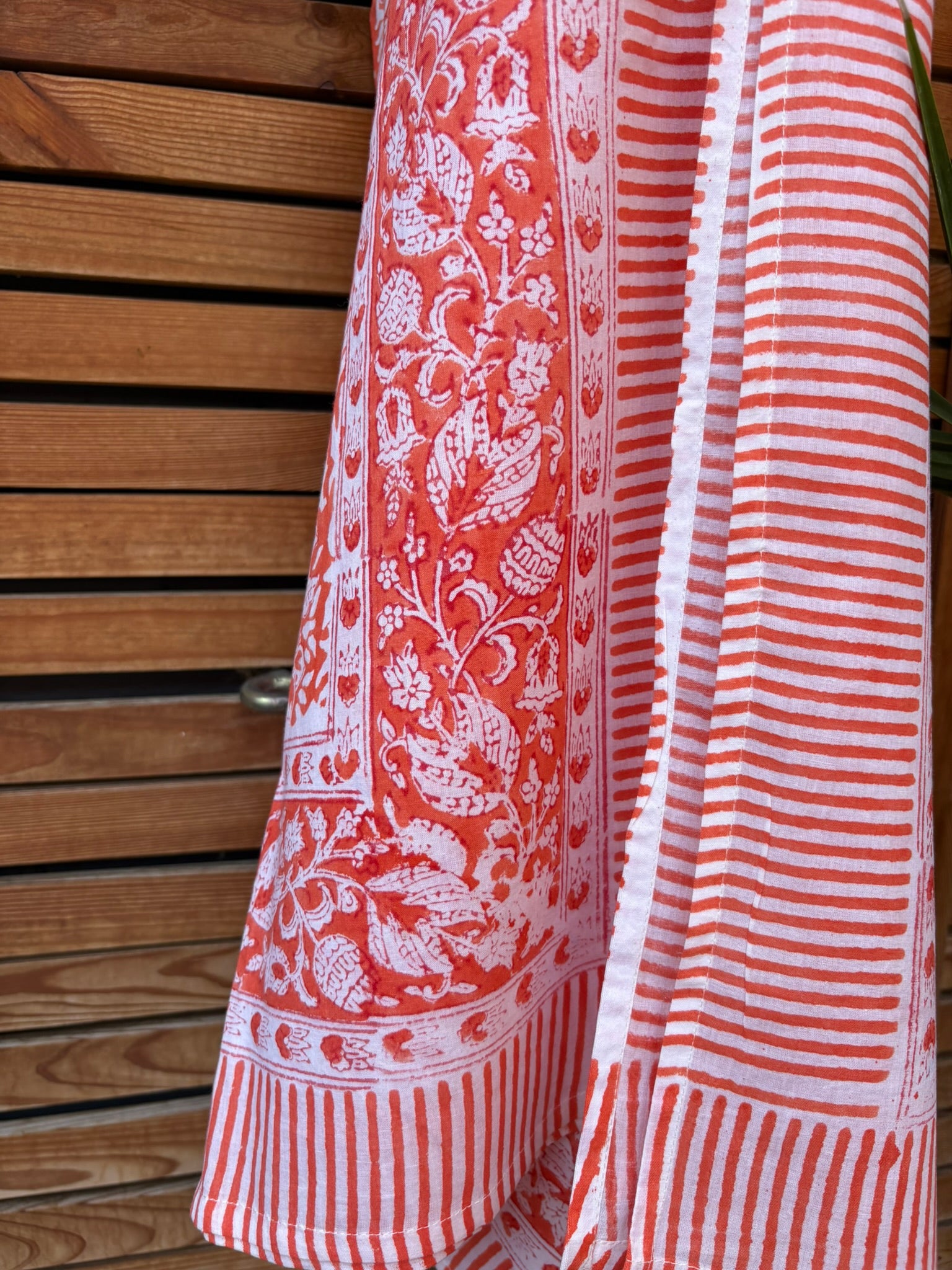 Paréo en coton léger avec impression artisanale indienne de type block print, présentant un motif floral complexe et une large bordure ornementale géométrique de couleur corail vif sur fond blanc. 